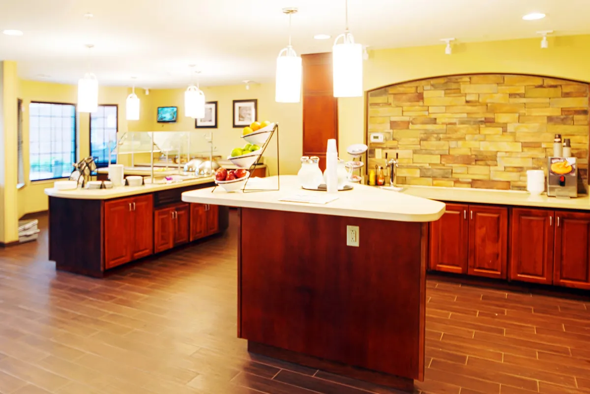 A cozy central kitchen island with a coffee station, fruit display, and stone wall backdrop. The area is perfect for enjoying breakfast, sipping coffee, or having a relaxed conversation, adding to the suite's sense of homeliness and comfort.