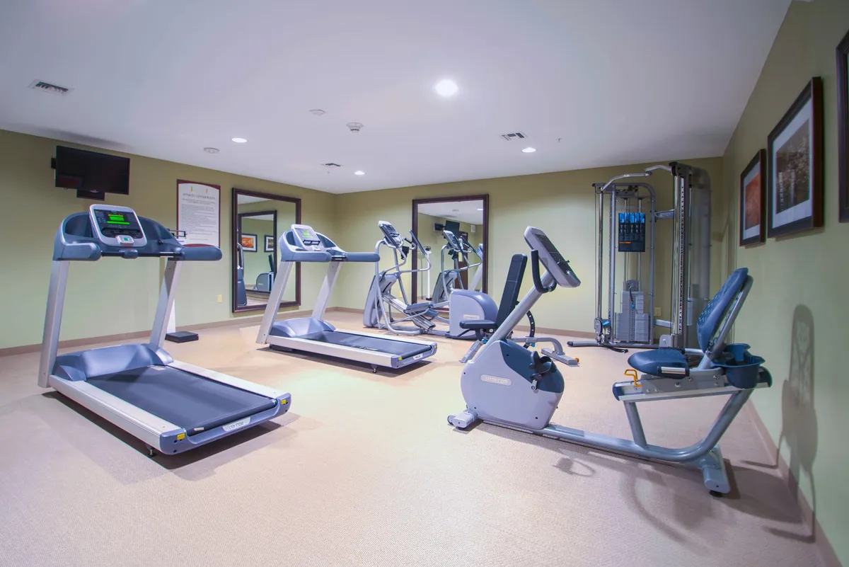 This interior image captures a well-equipped fitness center featuring treadmills, an elliptical machine, a recumbent bike, and a weight machine. Large mirrors and an open layout create an energizing, motivational environment for guests to maintain their workout routines.